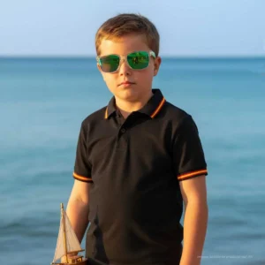 Niño con polo negro y detalles de la bandera de España en la playa